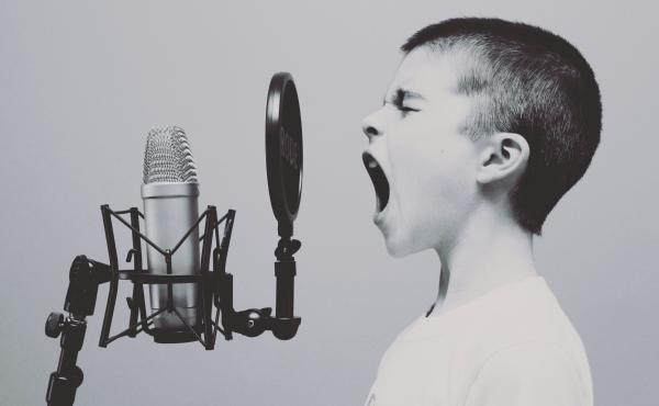 black & white image, young boy shouting into micropone