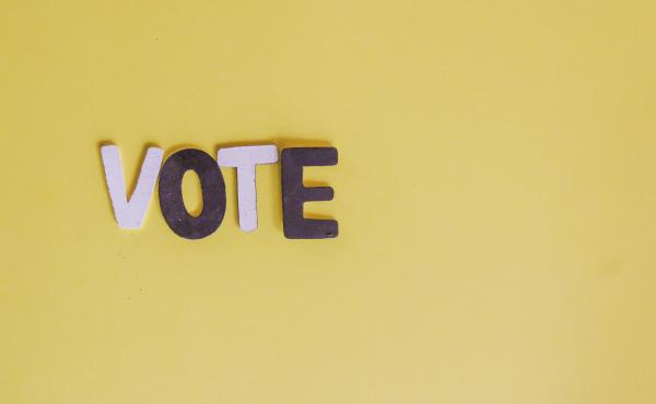 the letters vote arranged on a yellow background