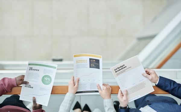 three sets of hands holding reports