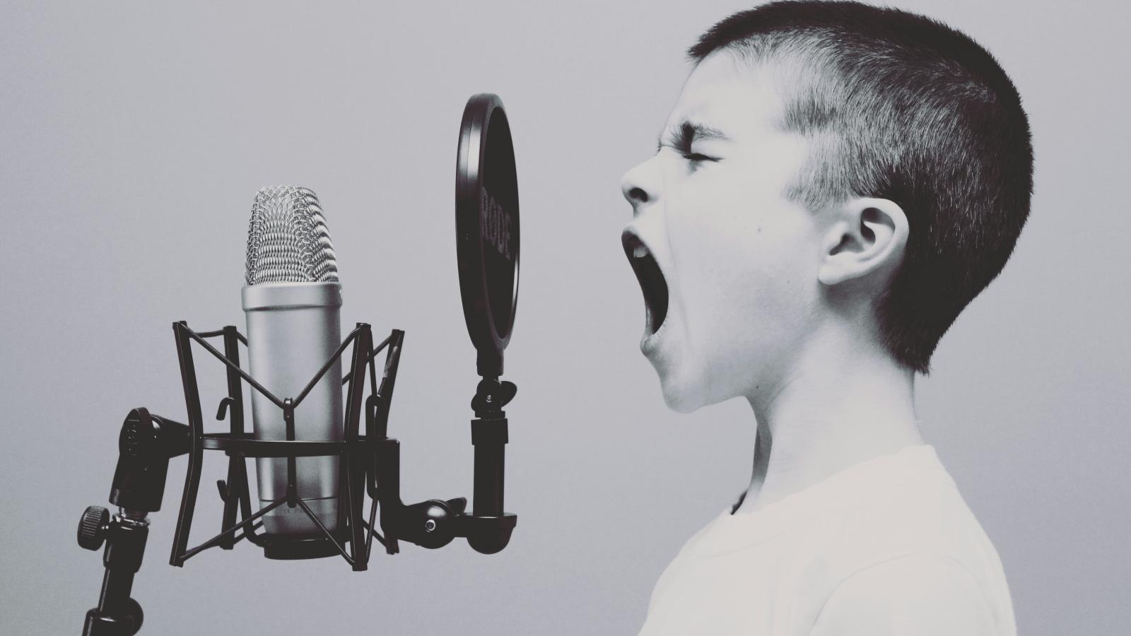 black & white image, young boy shouting into micropone